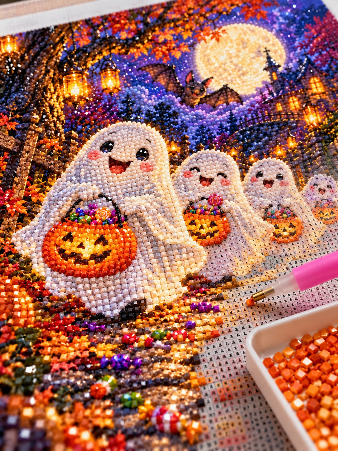 Close-up of the cute friendly ghosts trick-or-treating under the moon diamond painting in progress, square resin drills, wax pen and drill tray