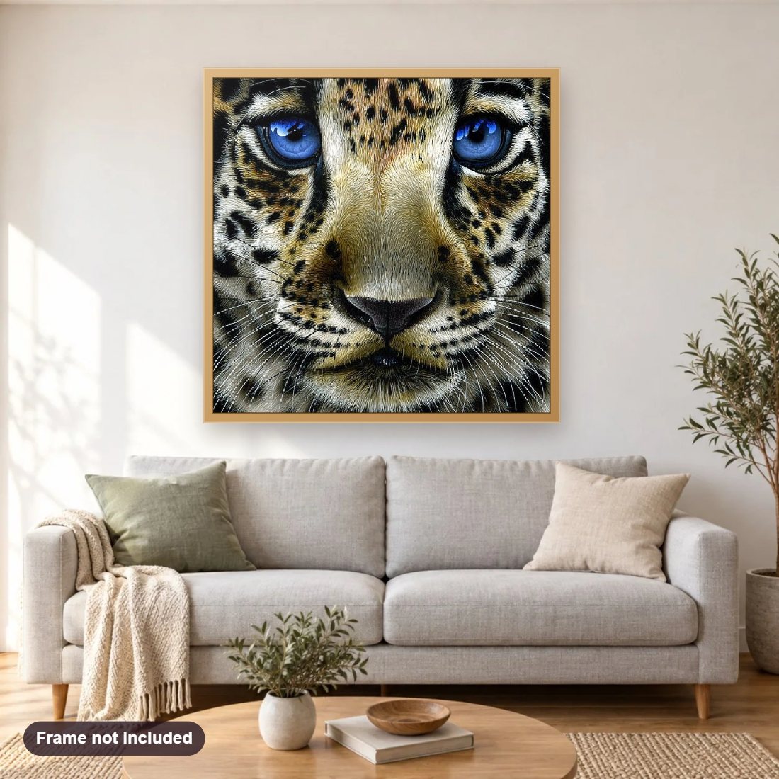 Leopard Cub with Blue Eyes diamond painting shown framed on a living room wall above a sofa