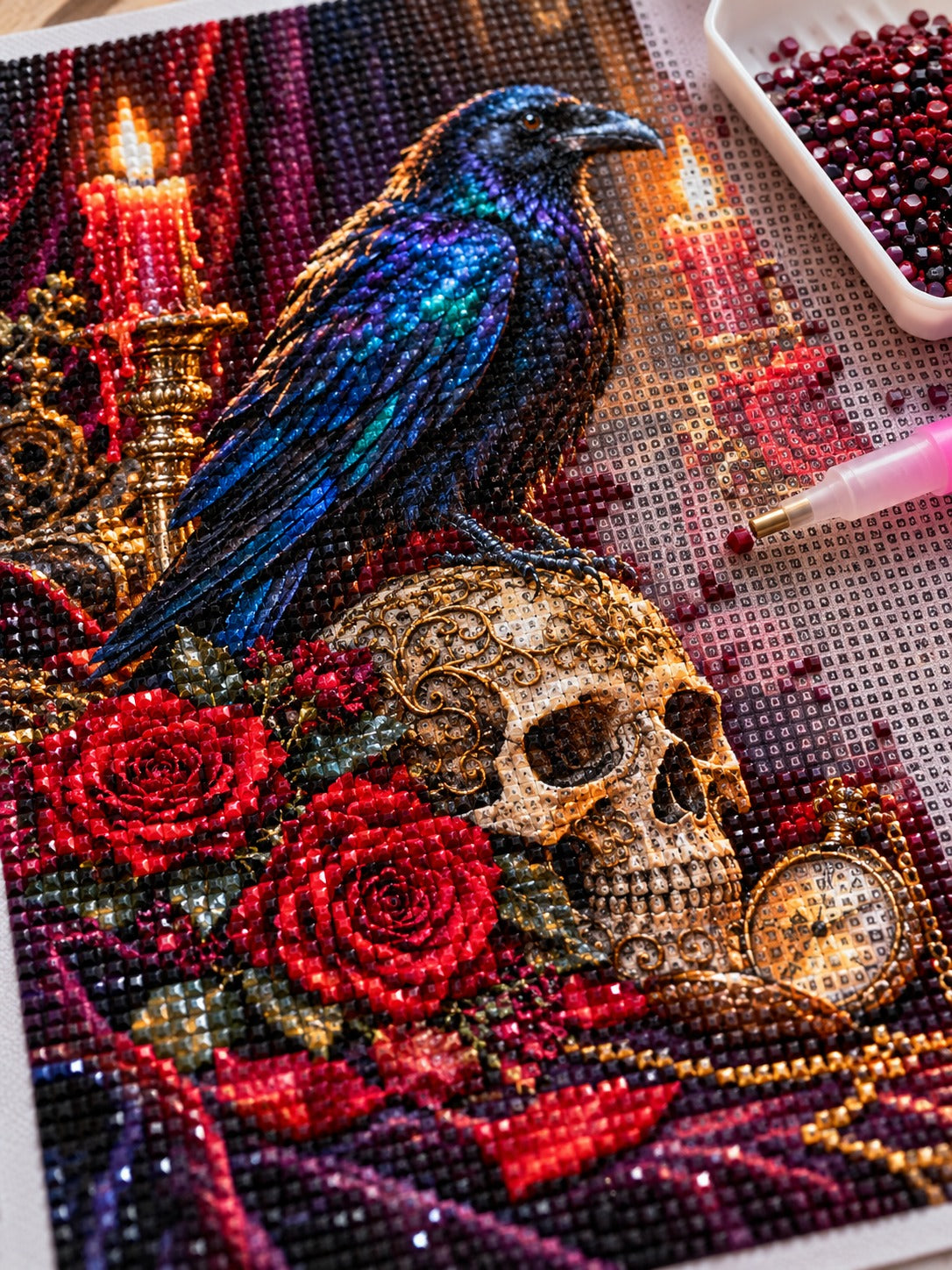 Close-up of the raven on a gothic skull with red roses and candles diamond painting in progress, square resin drills, wax pen and drill tray