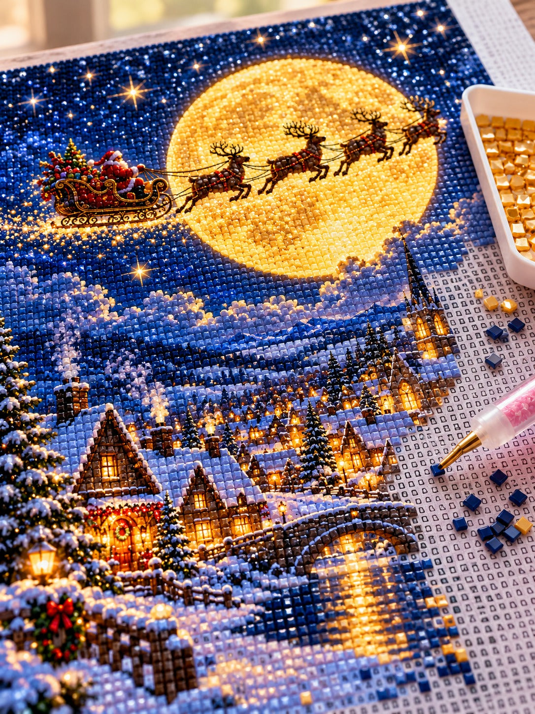 Close-up of the Santa's sleigh and reindeer crossing the golden Christmas moon diamond painting in progress, square resin drills, wax pen and drill tray