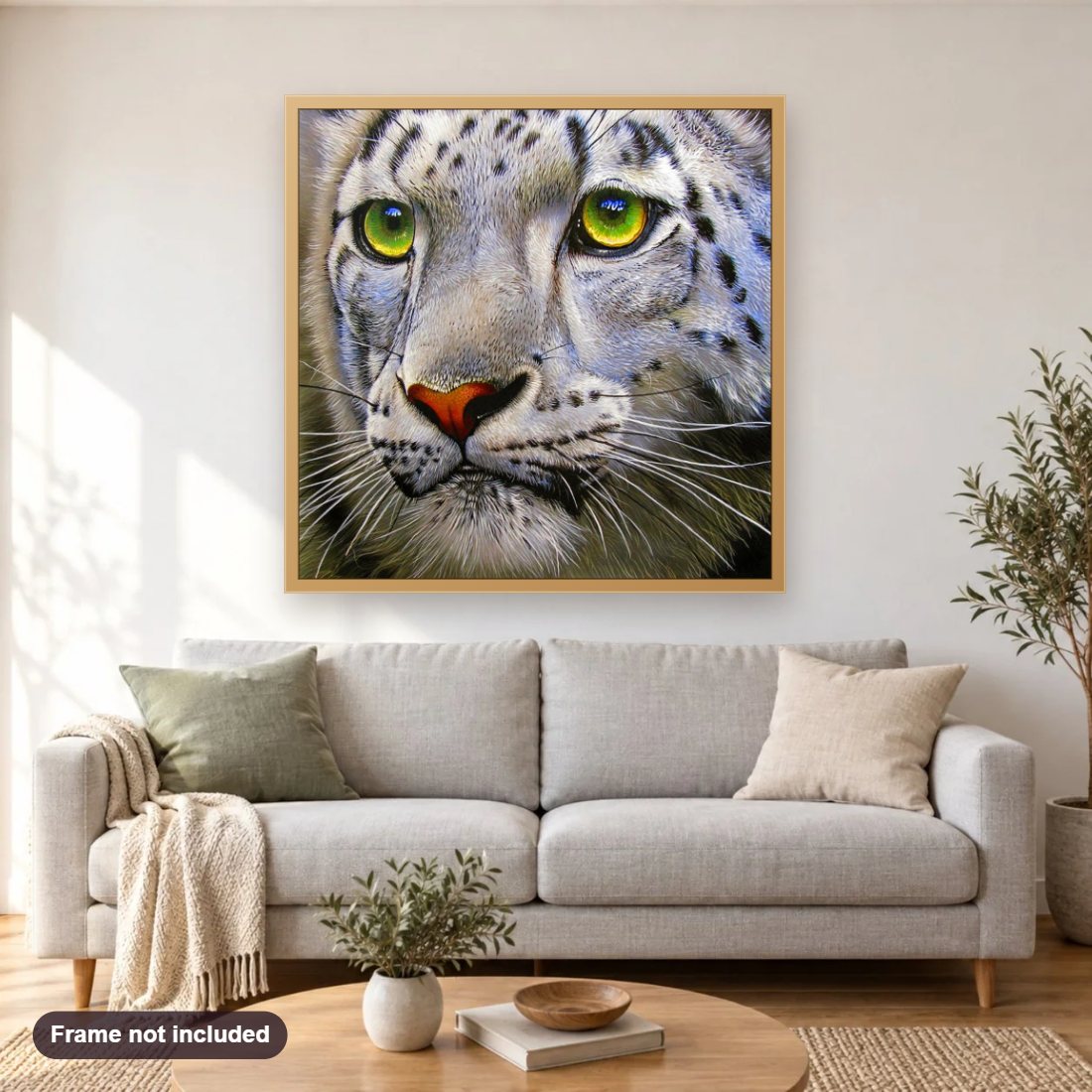 Snow Leopard with Green Eyes diamond painting shown framed on a living room wall above a sofa
