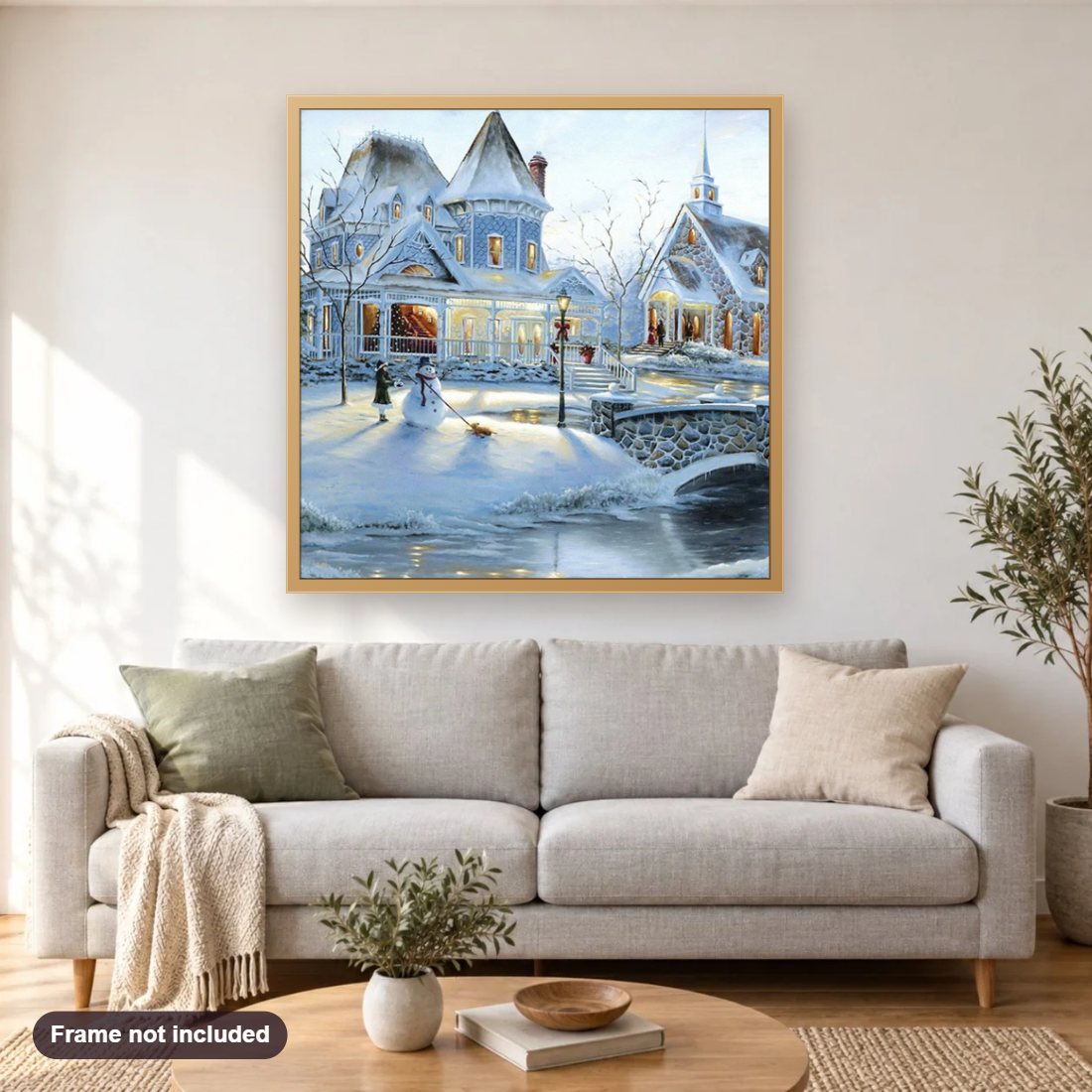 Snowy Town diamond painting shown framed on a living room wall above a sofa