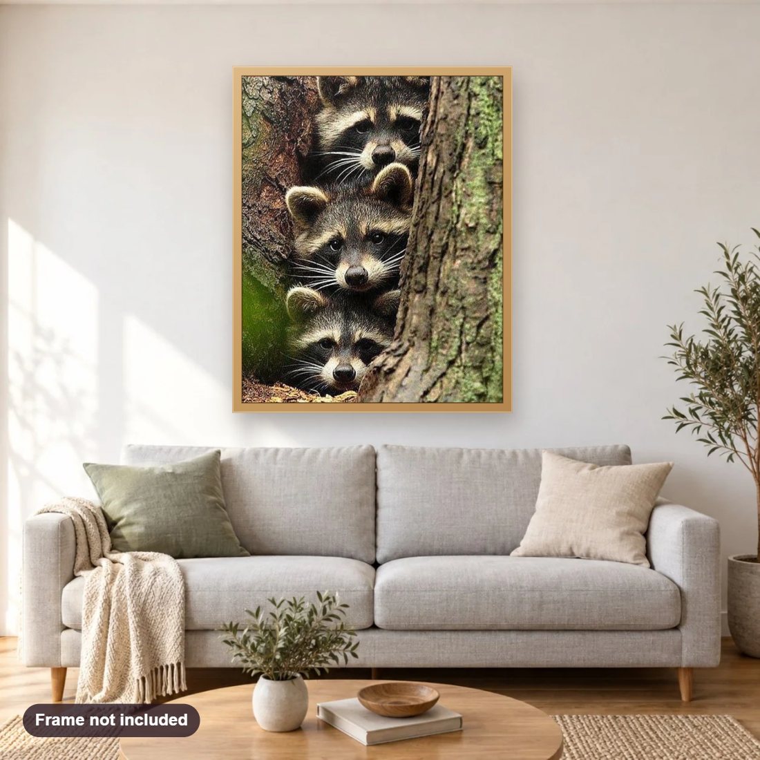 Three Raccoons Hiding in Tree diamond painting shown framed on a living room wall above a sofa
